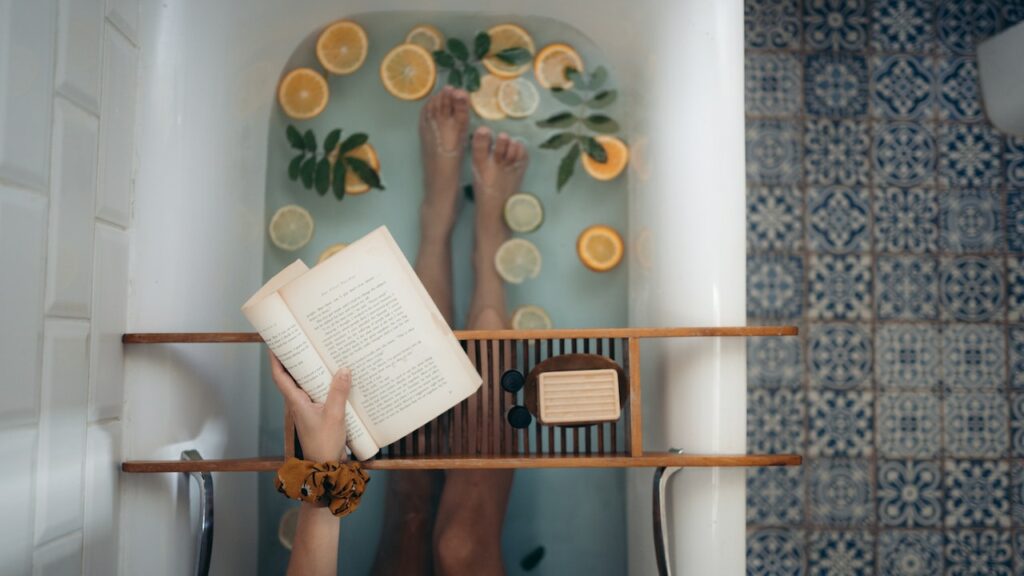arial shot of woman in bathtub doing her selfcare routine by reading a book